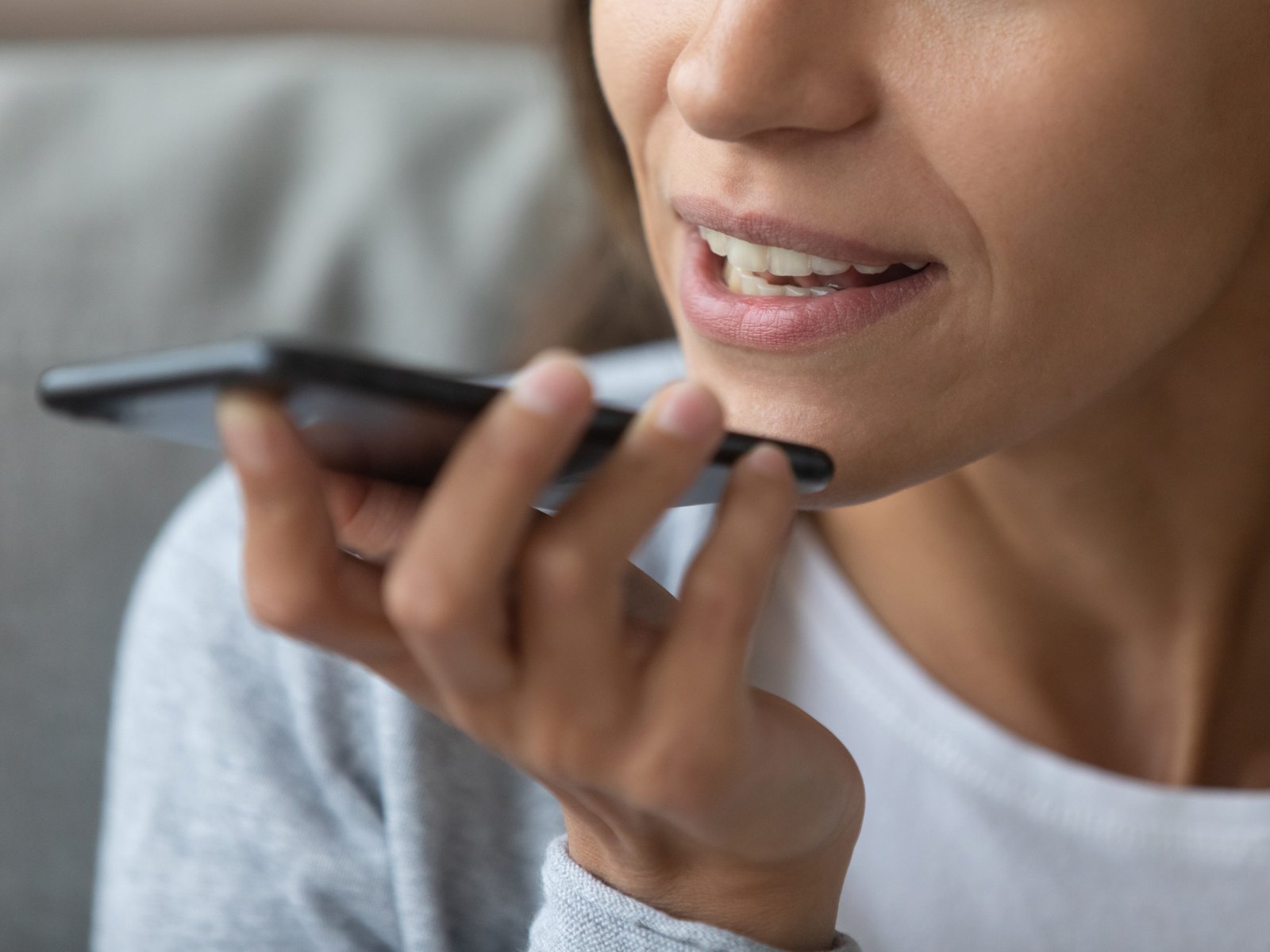 A close-up of a woman talking on speakerphone.