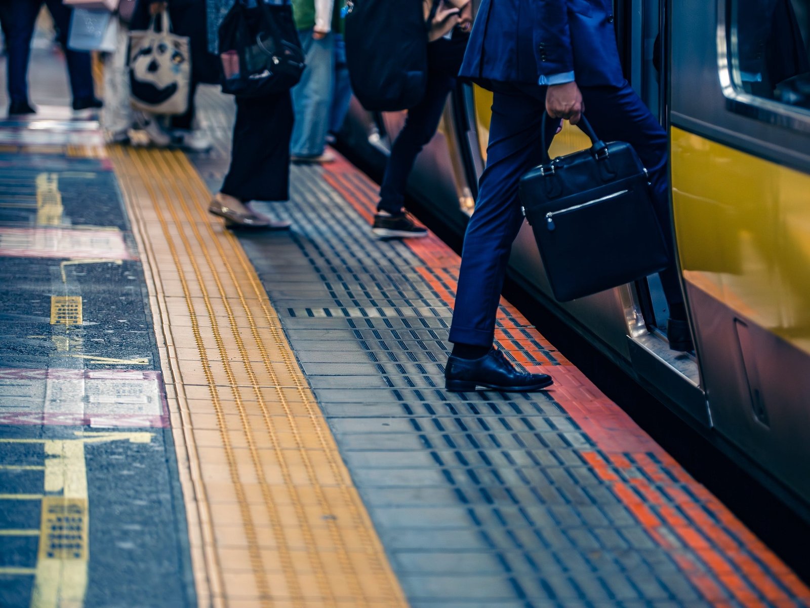 A shot of people boarding a train. The camera is focused only on travelers' legs as they're stepping from the platform to the train.