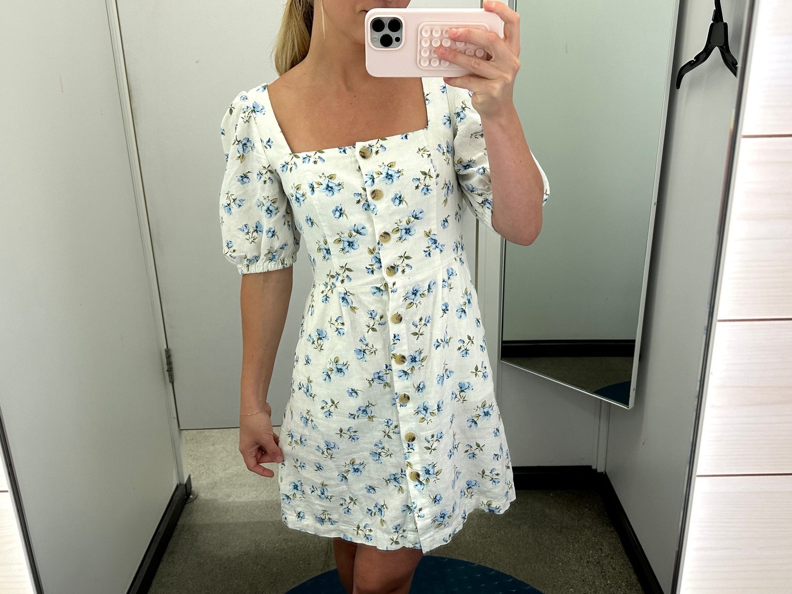 Chloe wearing a blue and white floral dress in an Old Navy fitting room.