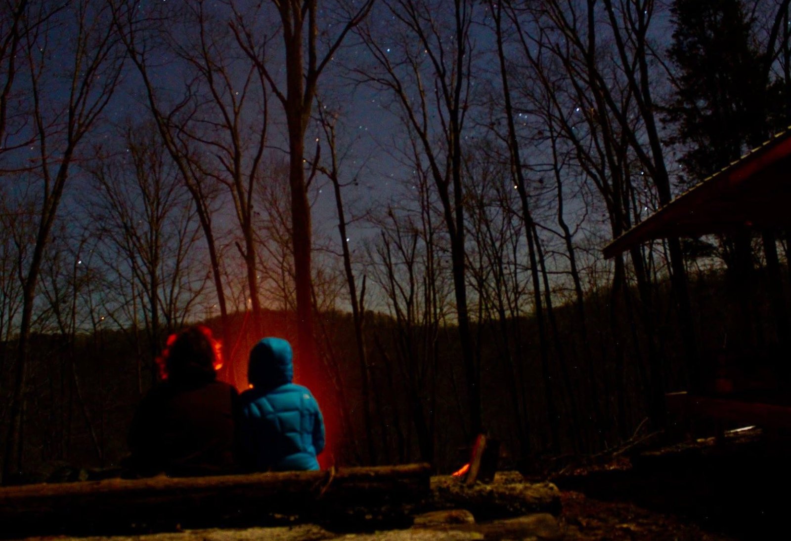 The writer sitting by a campfire near her cabin.