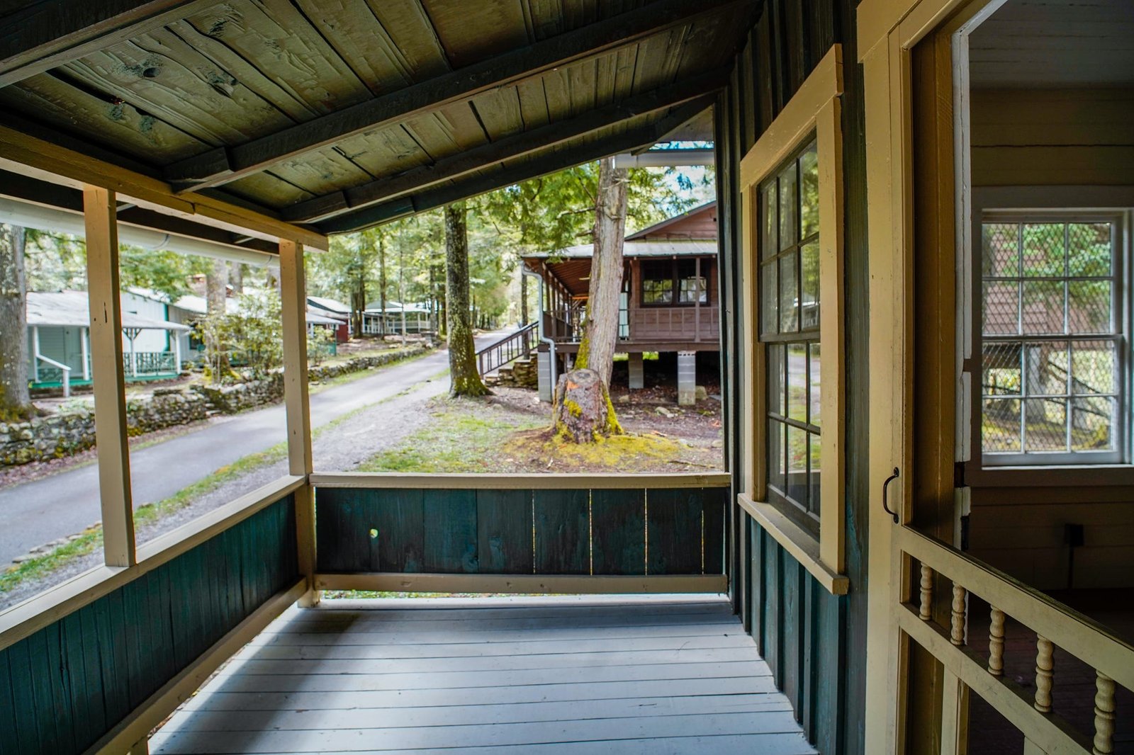 An emerald green porch with more cabins behind it