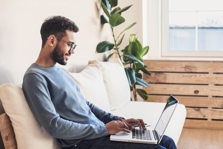 Young happy man using laptop to work as an editor or developer