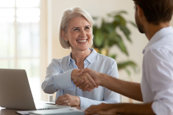 An older worker shakes hands at a job interview