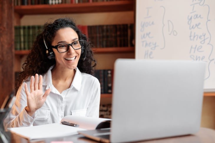 Distance education or online teaching. A woman in a headset has a virtual class using a laptop.