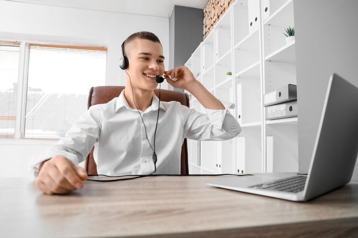 Young man wearing a headset working at a laptop