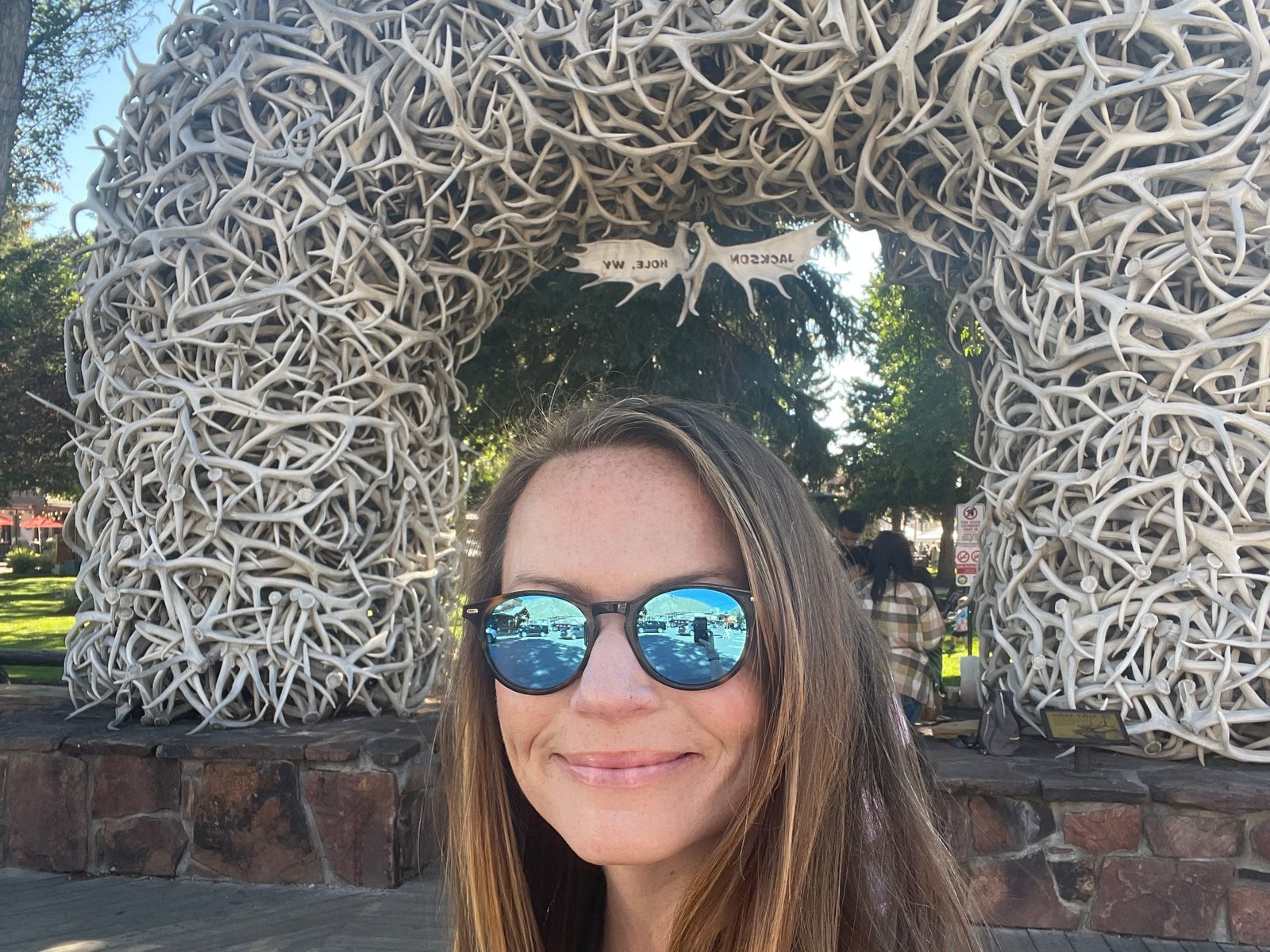 Emily posing in front of an arch made of elk antlers in the Town Square of Wyoming, Jackson.