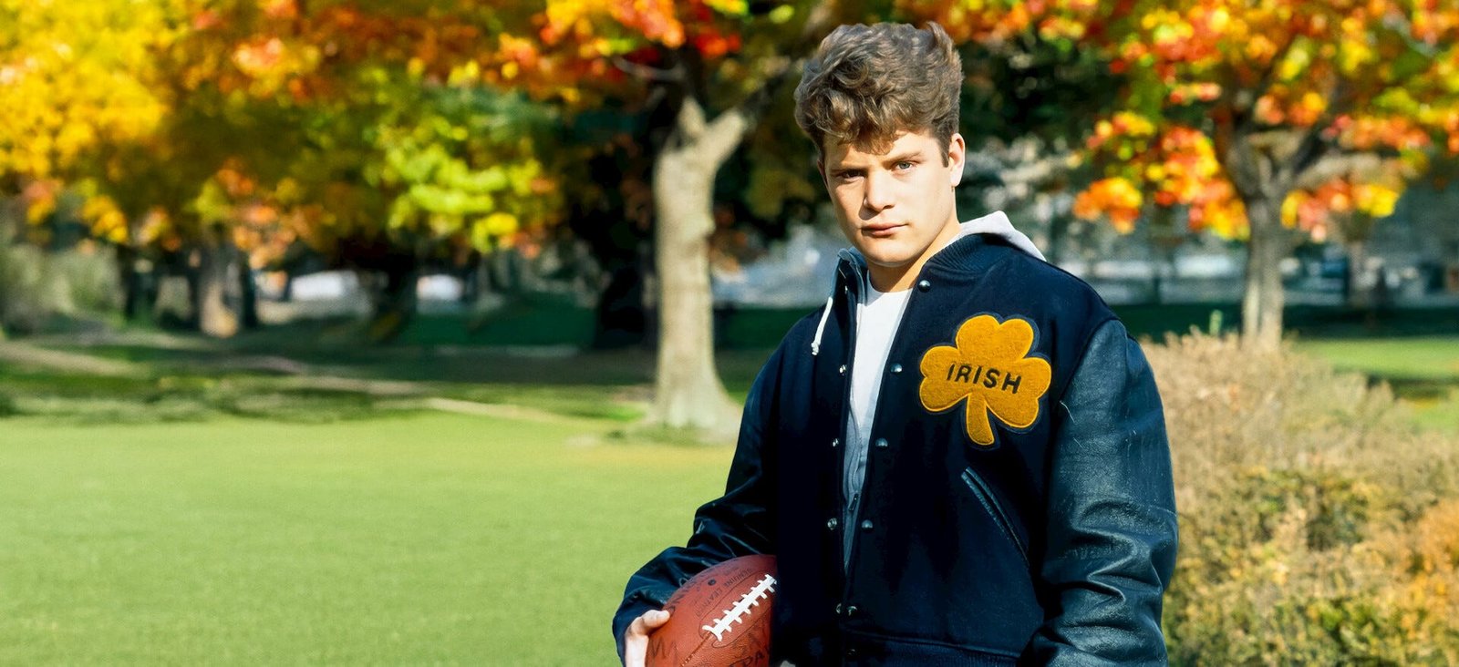 Sean Astin in a Notre Dame jacket holding a football