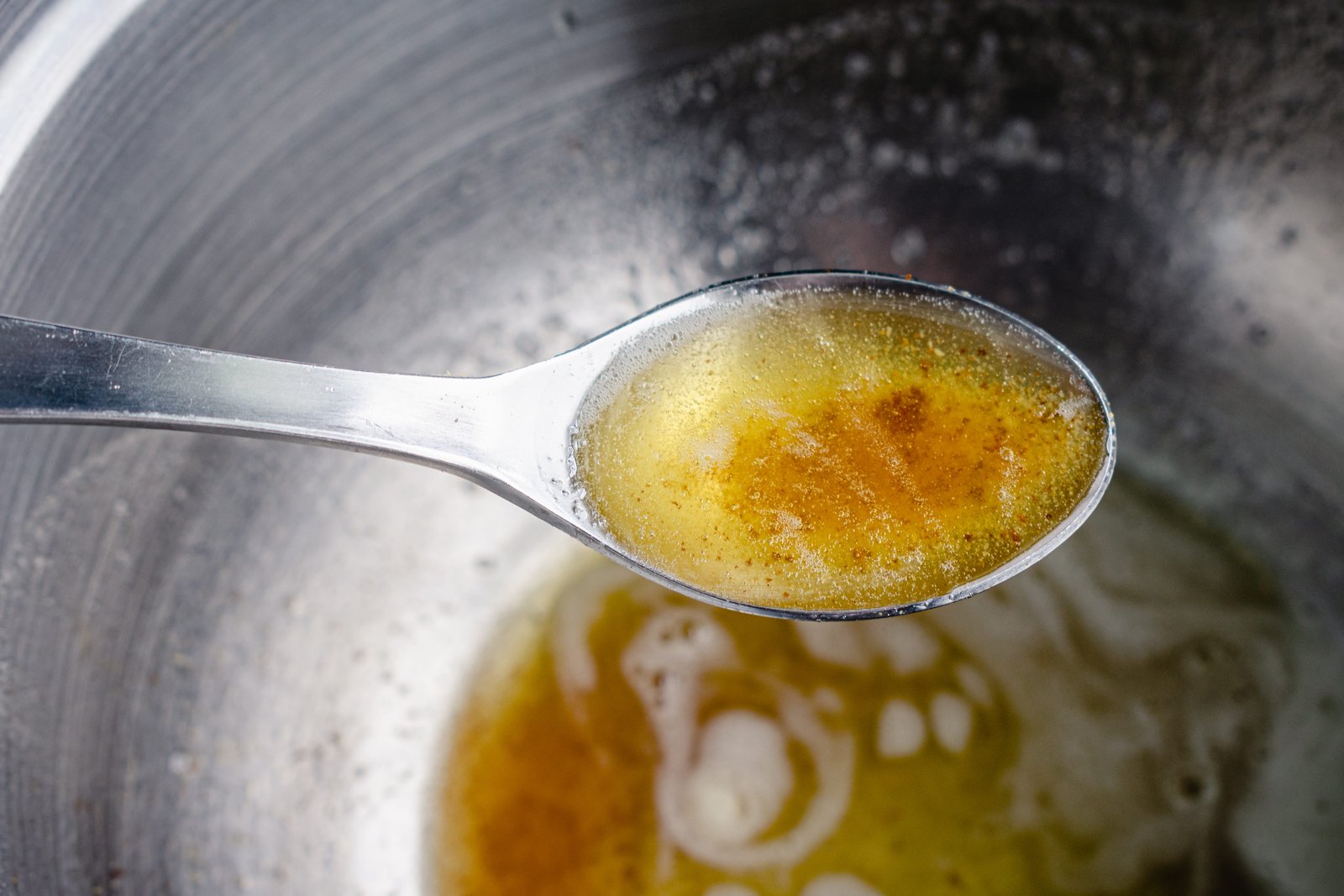 Browned butter in spoon held over mixing bowl
