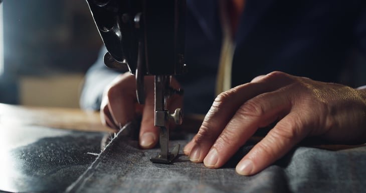 Experienced tailor sewing custom, high-quality apparel in a traditional tailoring workshop.