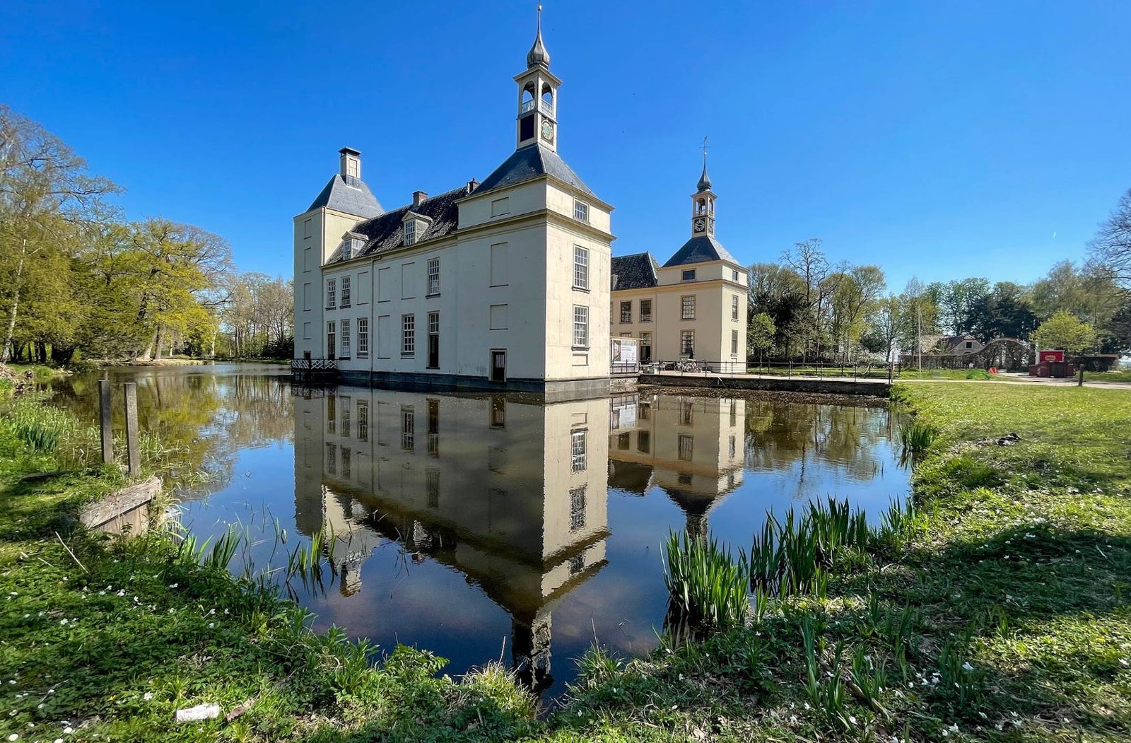 Huys te Warmont, a historic country estate with a moat, surrounded by water and grass.